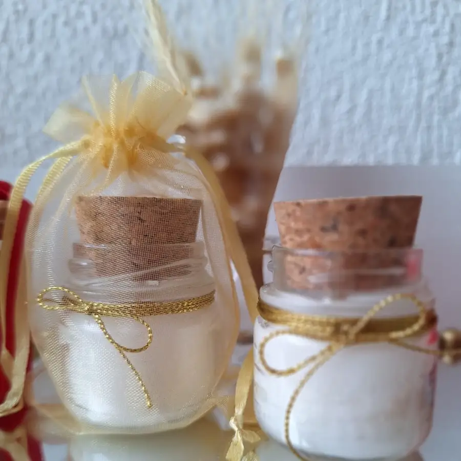 Vela aromática em vidro com tampa de rolha, embrulhada em saquinho de organza dourado